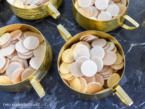 Kelche voller Hostien stehen auf einem Tisch.