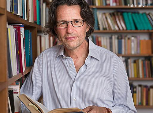 Der Philosoph Albert Kitzler steht in seiner Bibliothek.