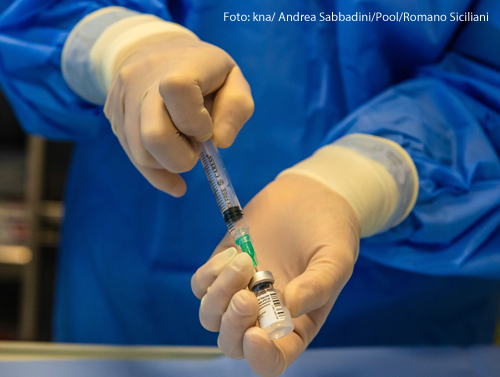 Ein Arzt zieht eine Spritze mit Corona-Impfstoff auf 