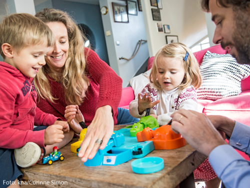 Eine Familie sitzt an eine Tisch und spielt.