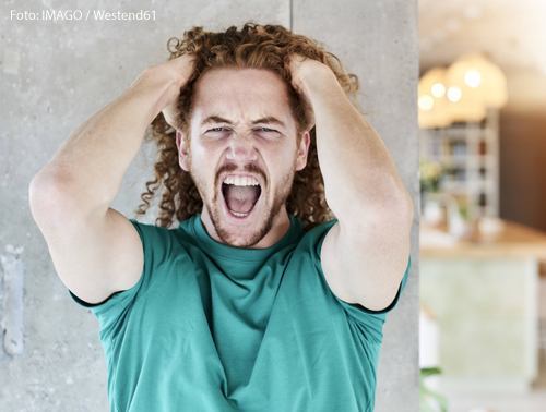 Ein Mann hält sich die Hände an den Kopf und schreit. 