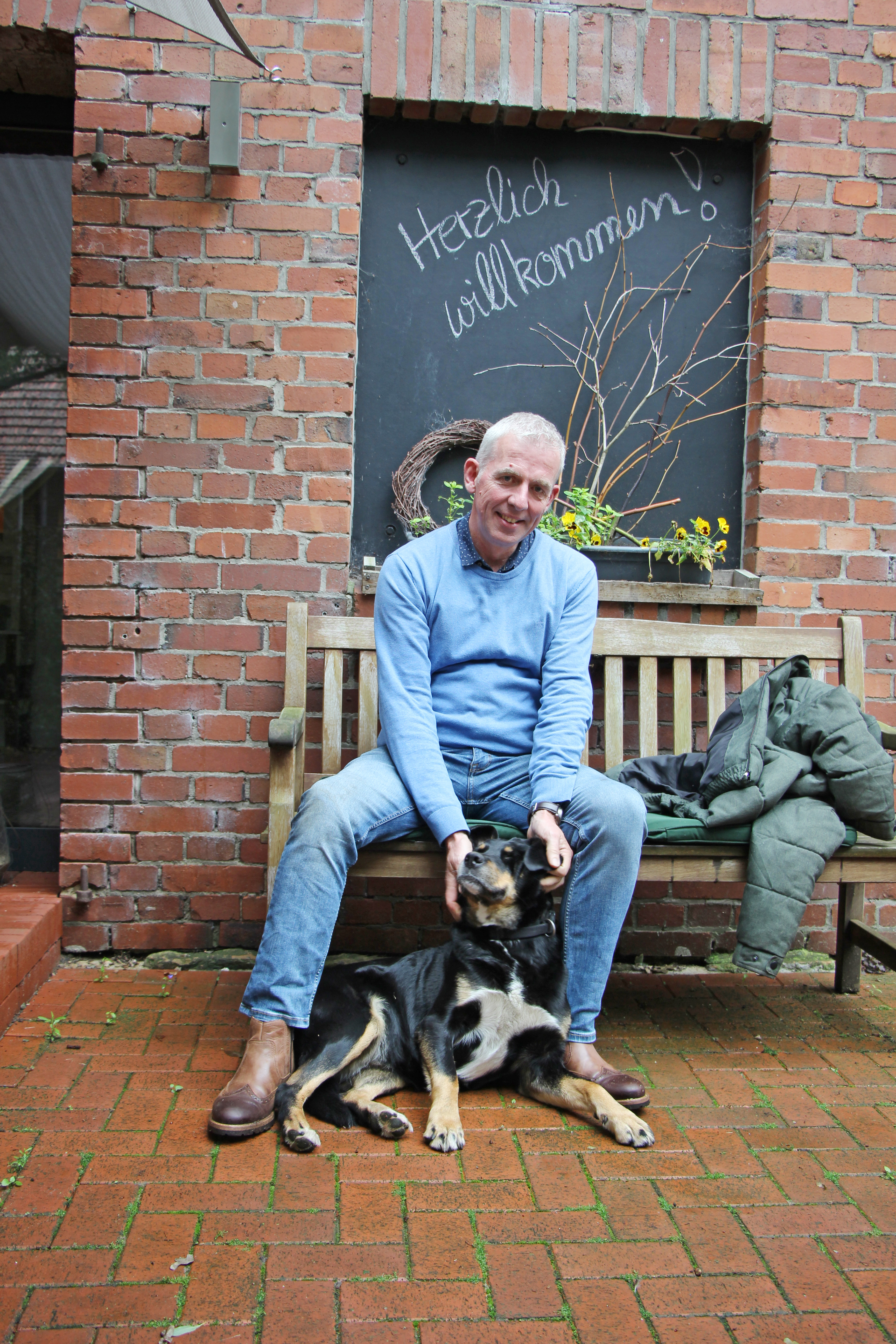 Andreas Brinker sitzt auf einer Bank mit seinem Hund 