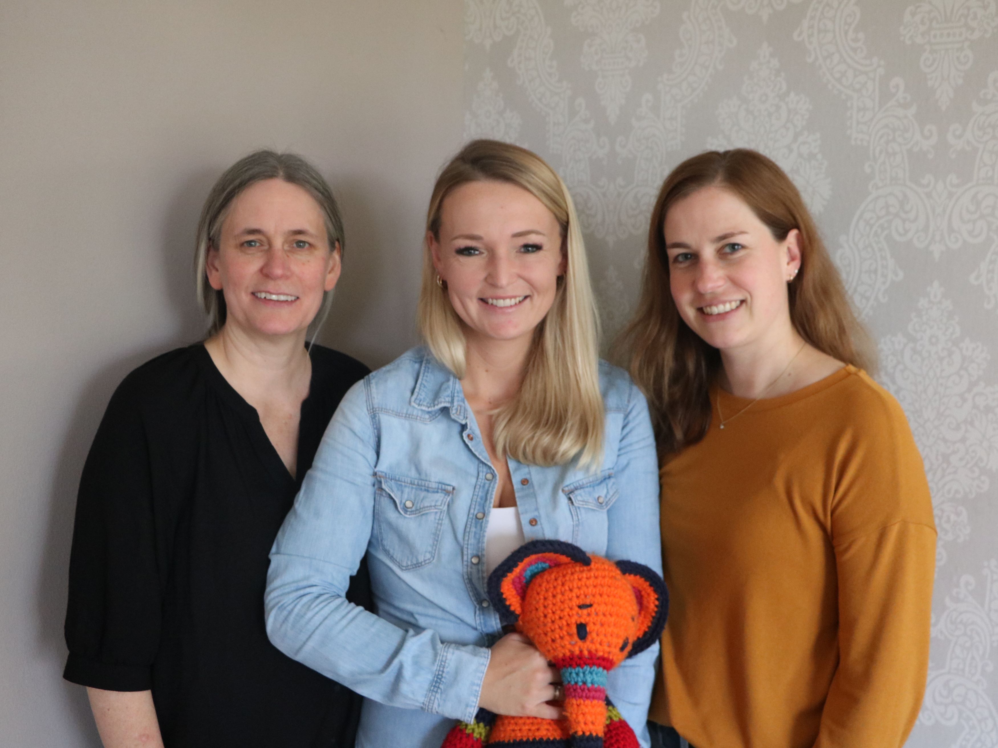 Drei Frauen stehen nebeneinander und halten einen Elefanten aus Stoff in der Hand