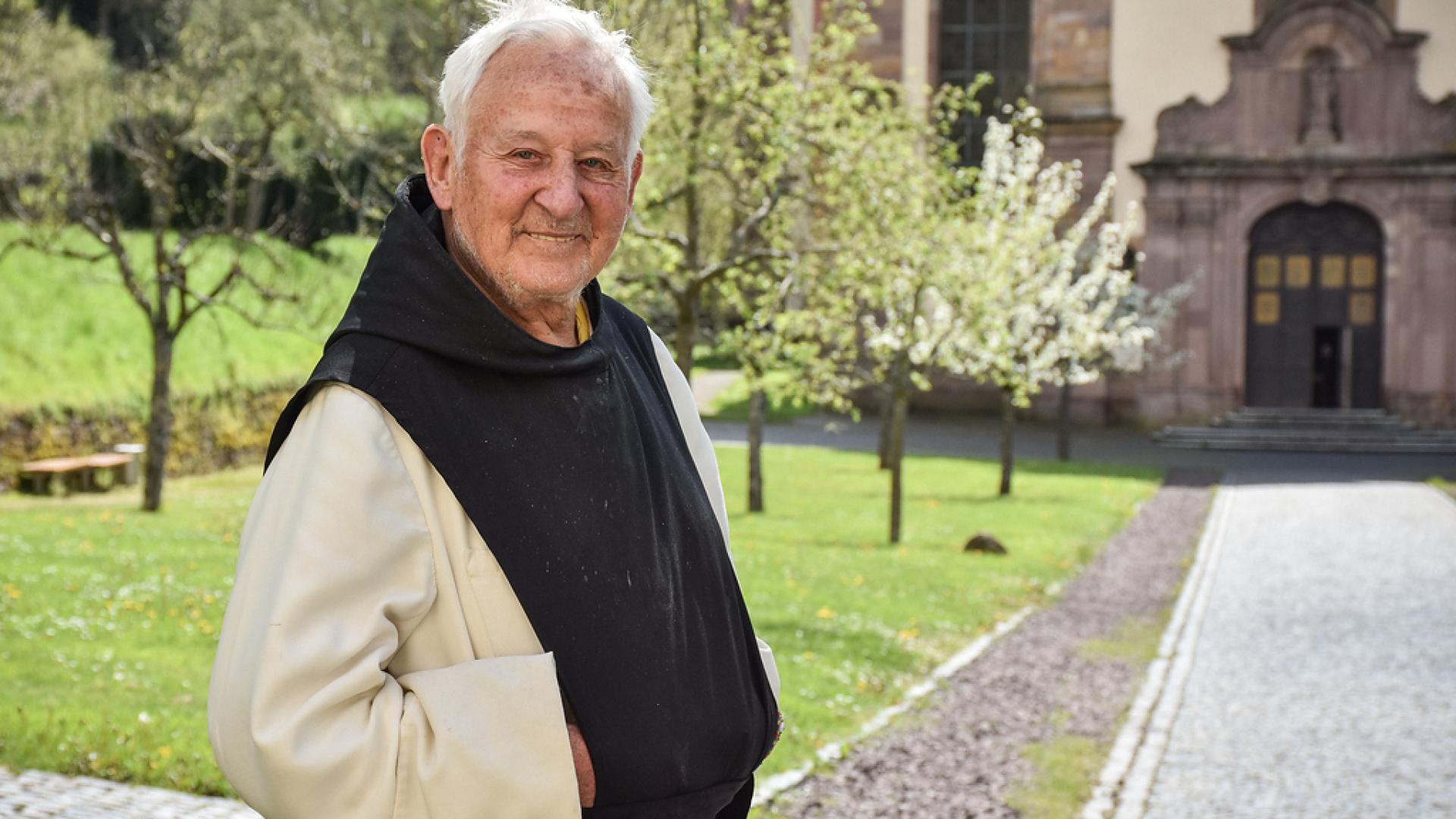 Mönch steht vor Klosterkirche