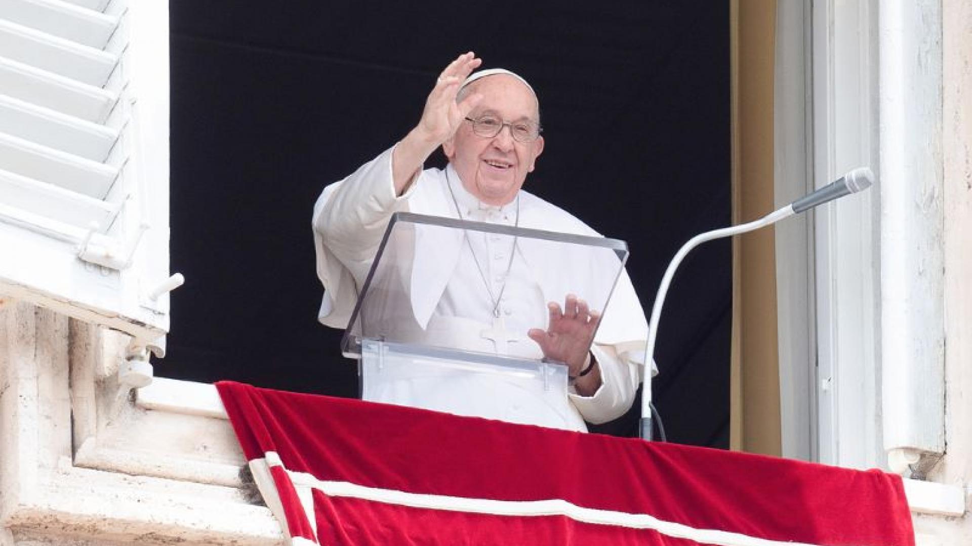 Papst Franziskus steht winkend am Fenster 