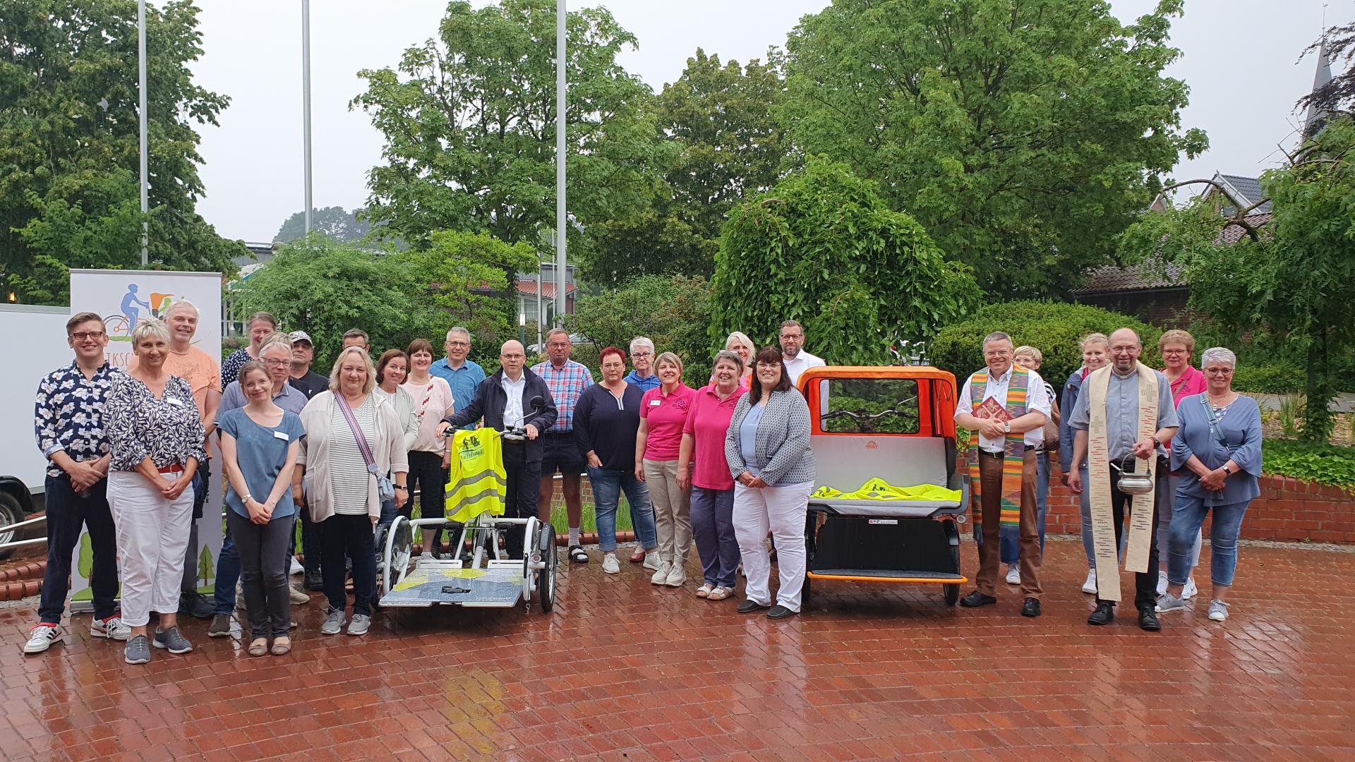 Viele Menschen stehen neben zwei Fahrrad-Rikschas zusammen. 