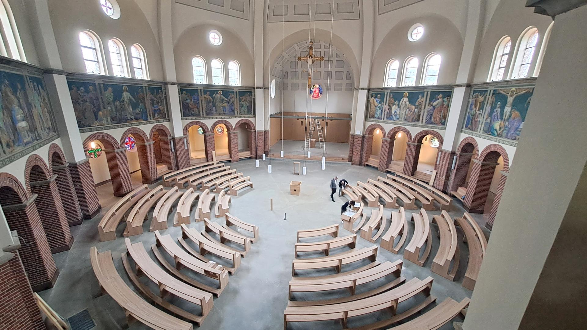 Der Blick von oben in eine Kirche mit Bänken, die im Kreis aufgestellt sind. 