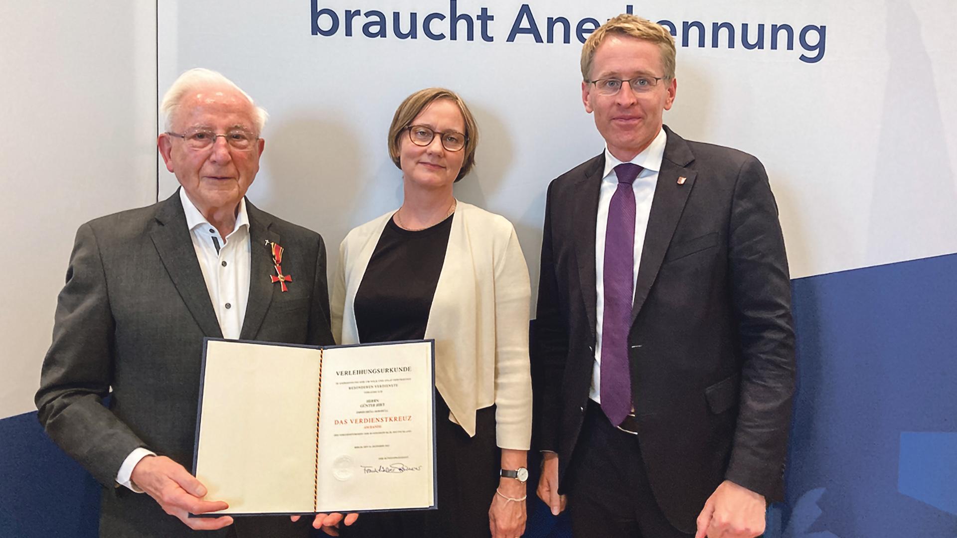 Günter Hirt mit Katja Heidemanns von Missio und Ministerpräsident Daniel Günther bei der Verleihung des Bundesverdienstkreuzes in Kiel.