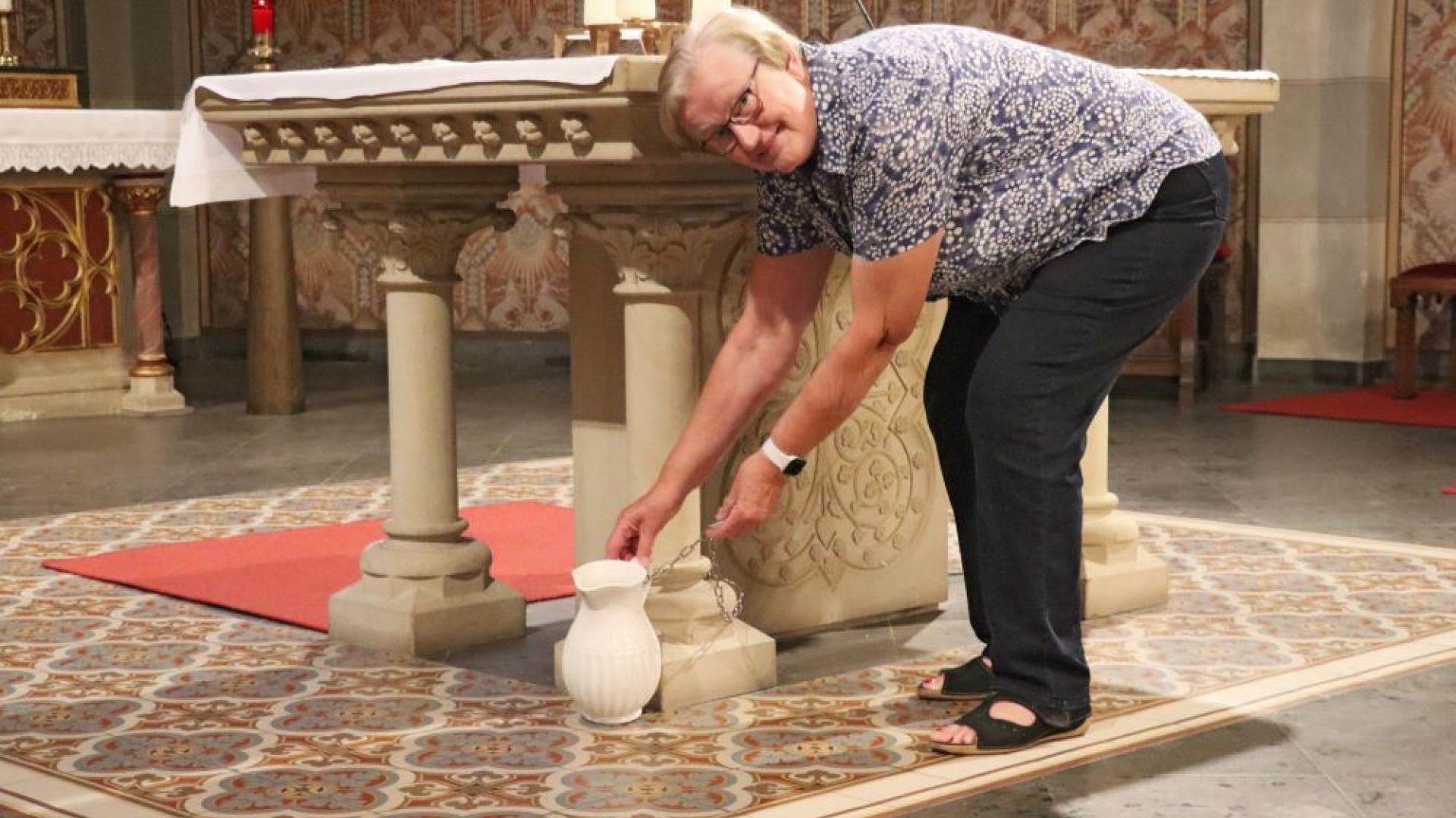 Frau vor einem Taufkrug in der Kirche