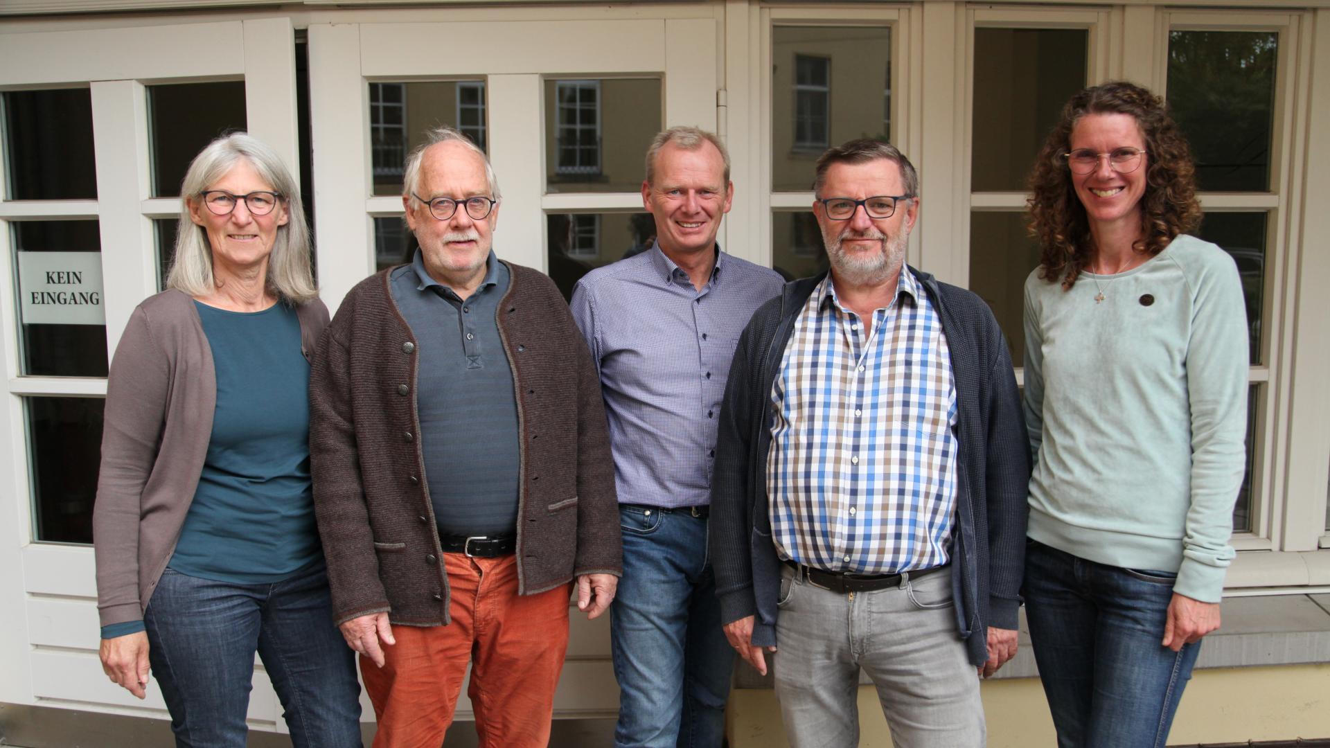 Fünf Personen stehen vor einer Fensterfront