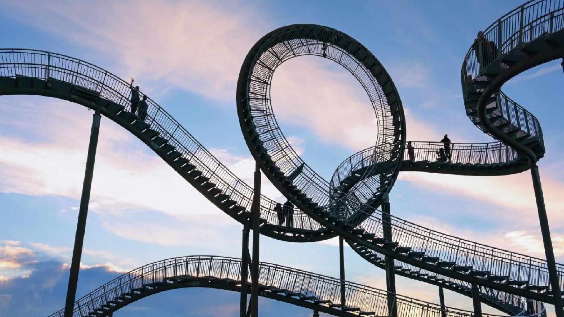 Eine geschwungene Treppe, auf der Menschen gehen, im Hintergrund geht die Sonne unter
