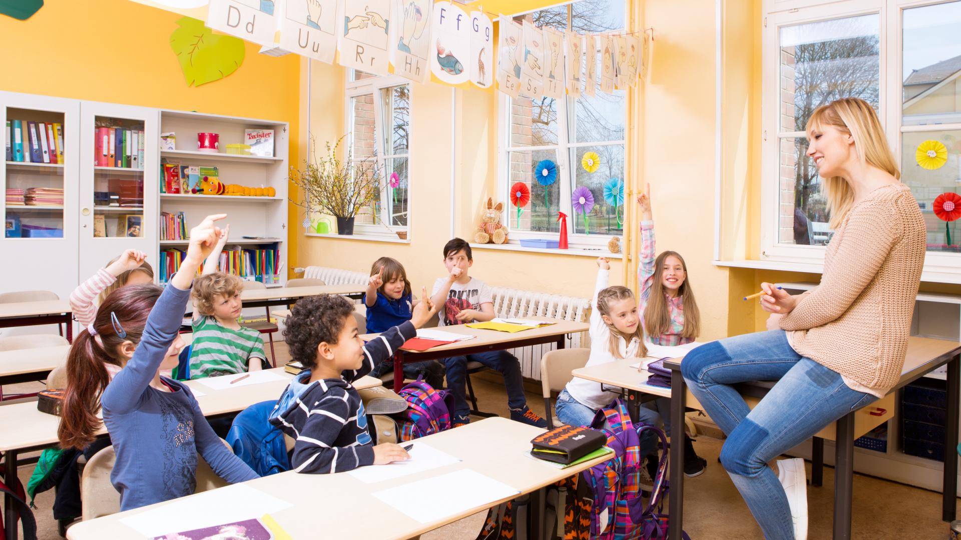 Eine Lehrerin sitzt auf dem Pult, ihr gegenüber einige Schüler