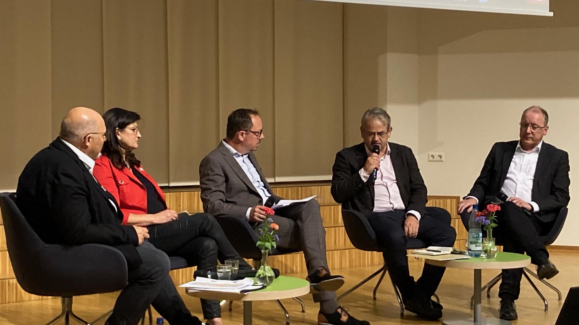 Fünf Menschen sitzen auf einer Bühne und sprechen miteinander.