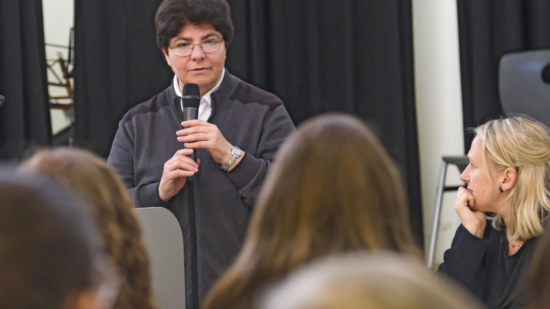 Eine Ordensschwester steht mit Mikrofon vor einer Gruppe von Schülern