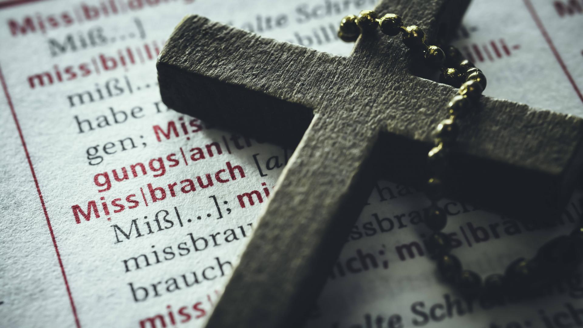 Ein Kreuz liegt auf einer aufgeschlagenen Buchseite