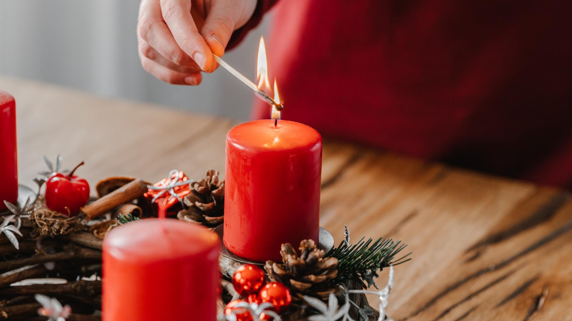 In Nahaufnahme zündet eine Hand eine Kerze an