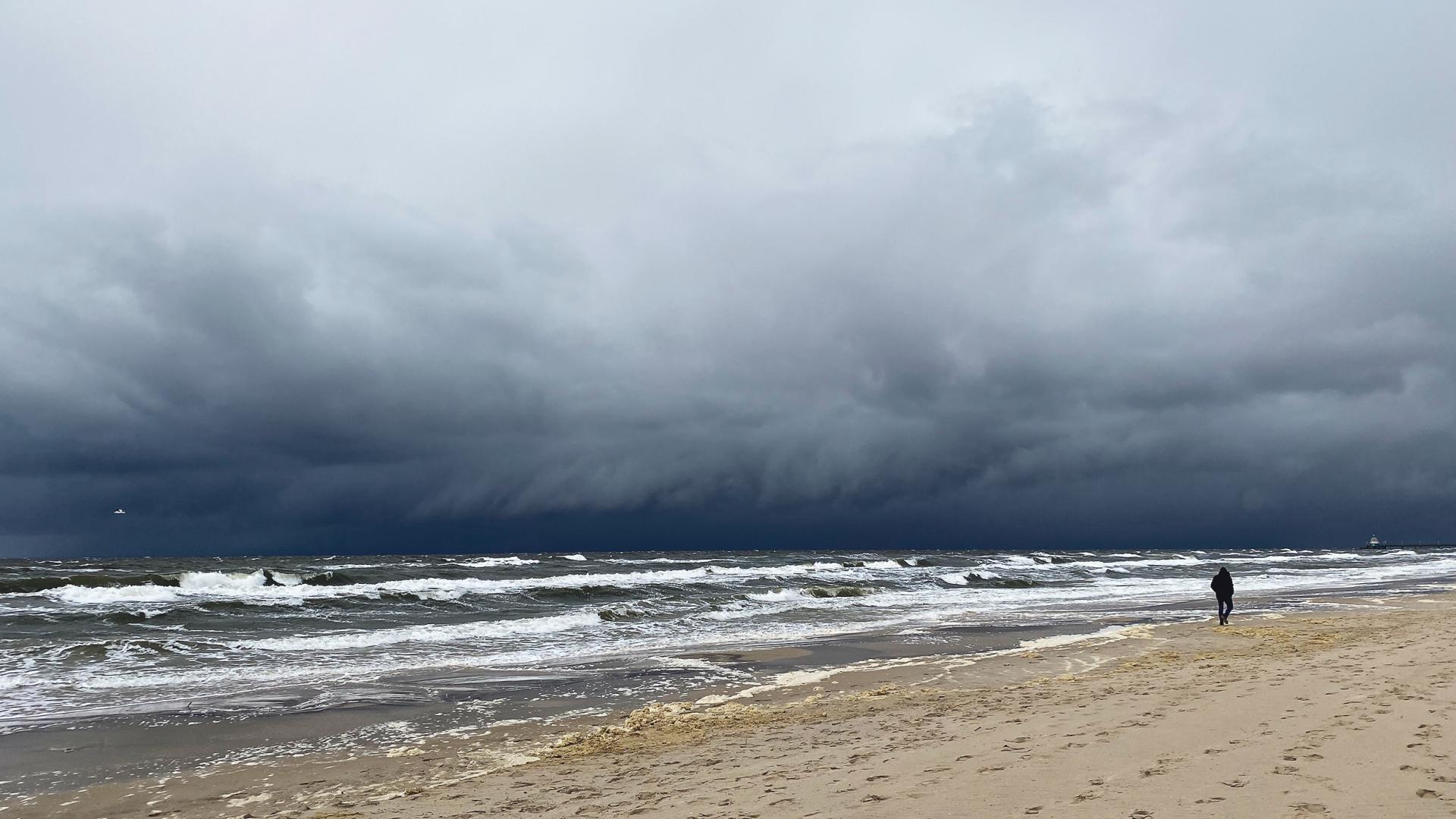 Person am Strand bei dunklem Himmel.