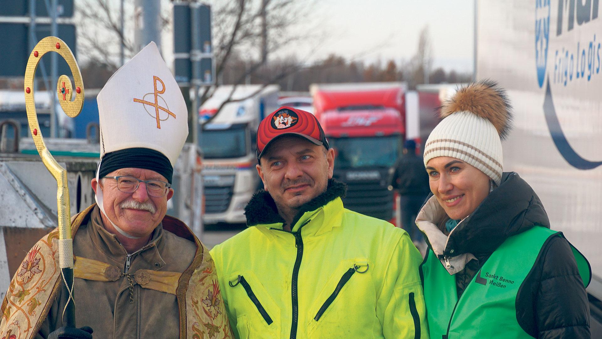 Drei Leute vor parkenden LKWs
