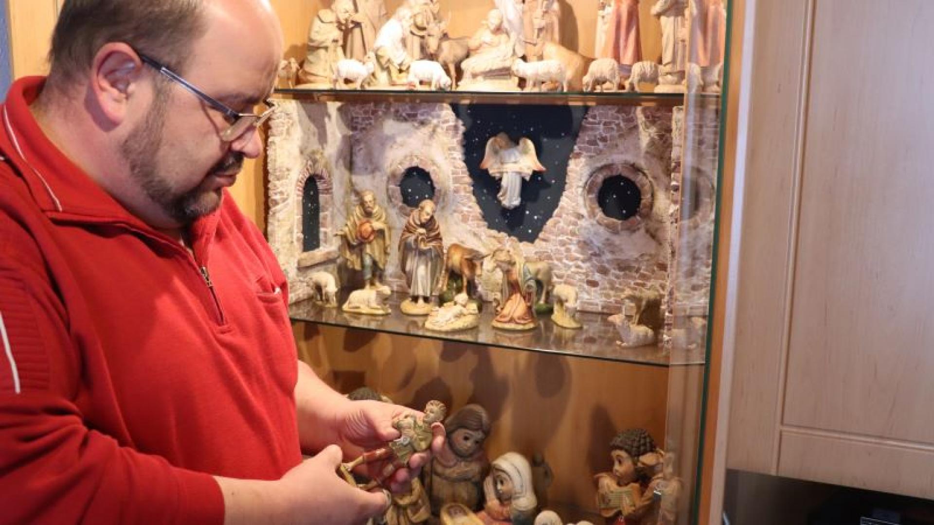 Ein Mann steht vor einer Vitrine mit Krippenfiguren