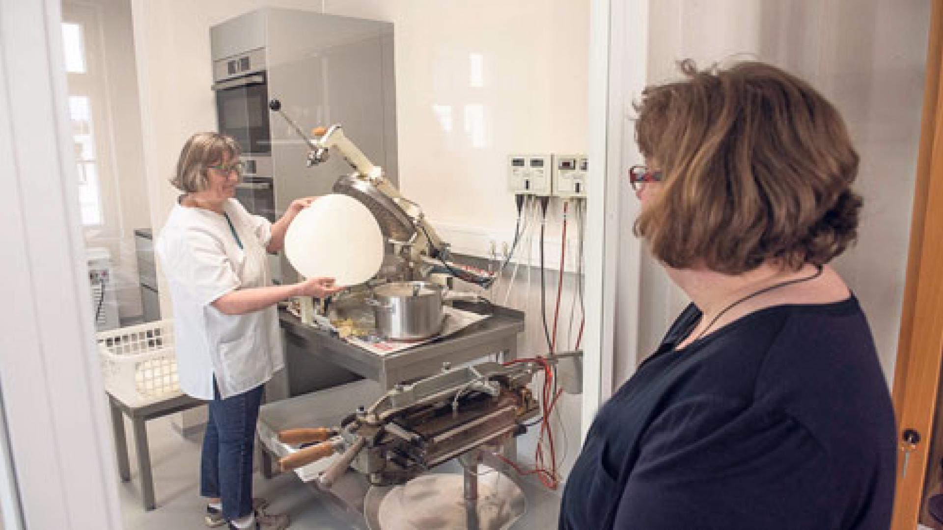 Eine Besucherin schaut der gehörlosen Carola Schmiedt durch die Glastür beim Backen der Hostien zu.
