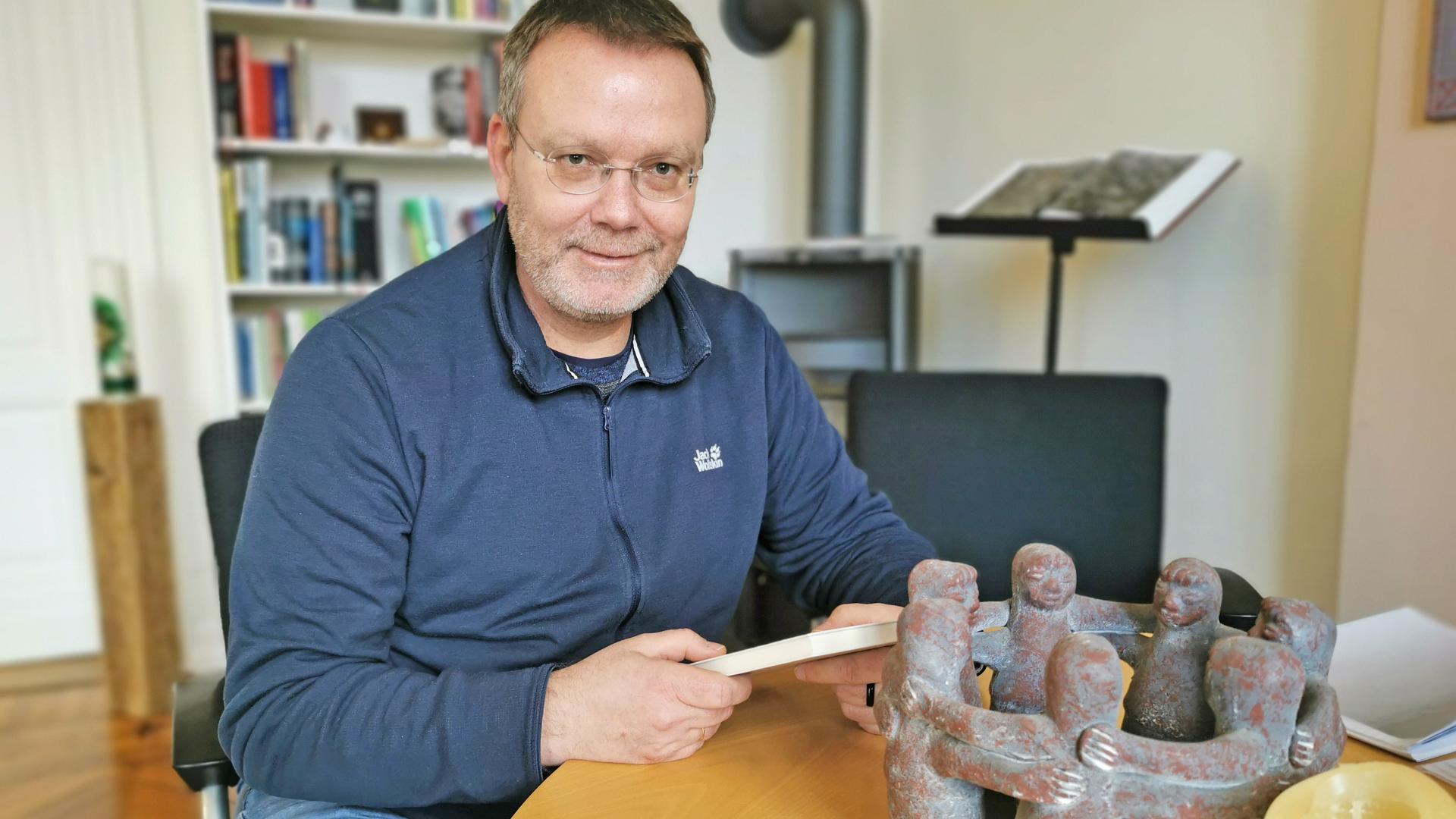 Ein Mann sitzt an einem Tisch und schaut den Betrachter an