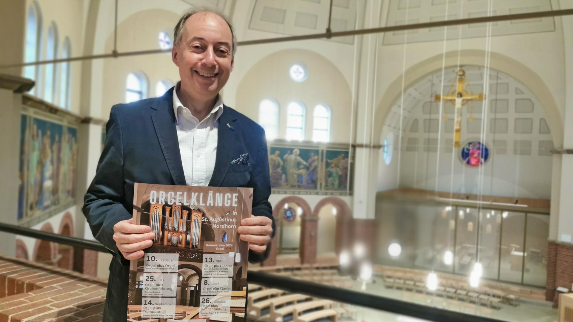 Ein Mann hält auf einer Orgelempore stehend ein Plakat in die Kamera