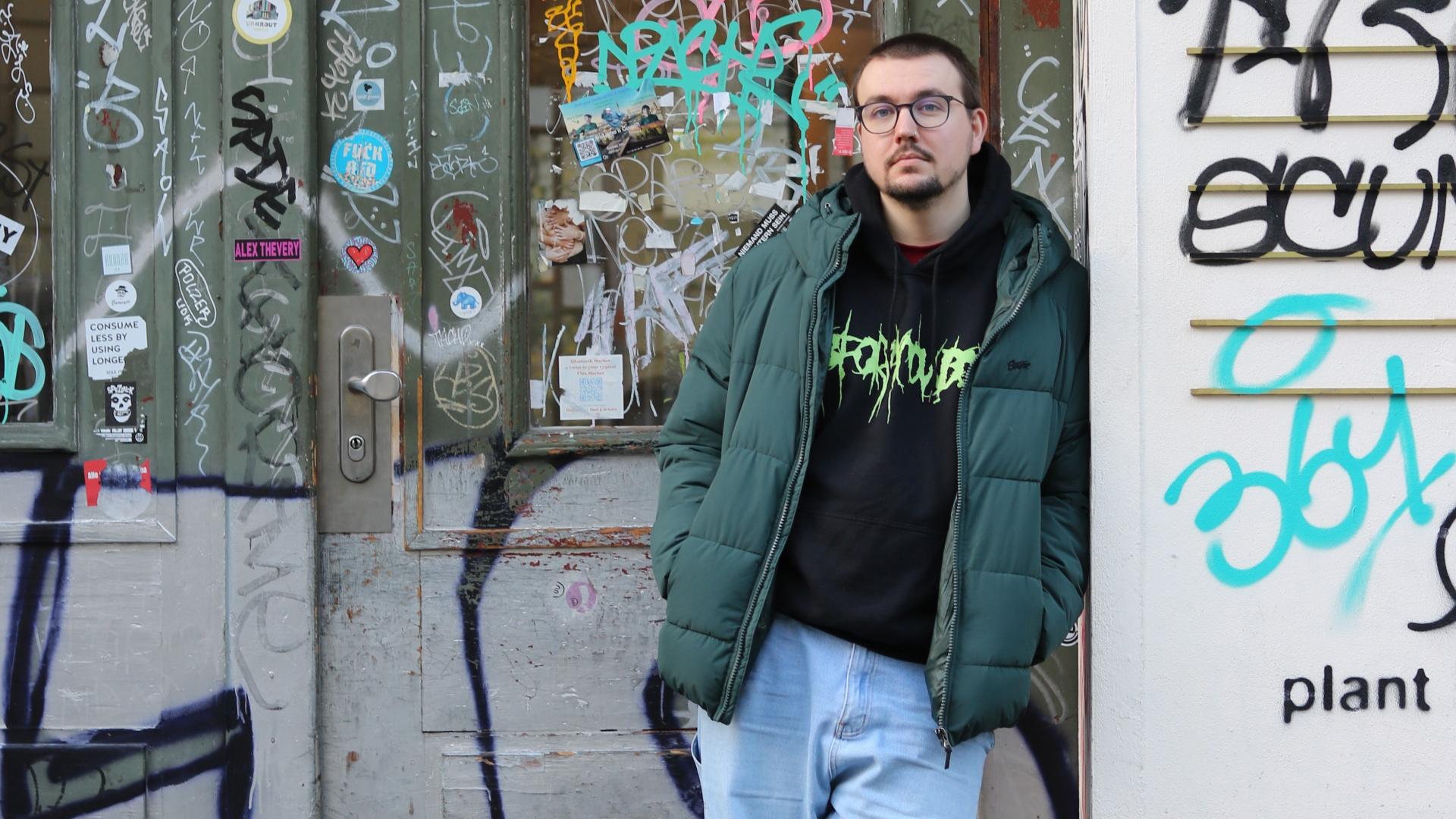 Fabian Kühnemann steht lässig vor einer Wand mit Graffiti