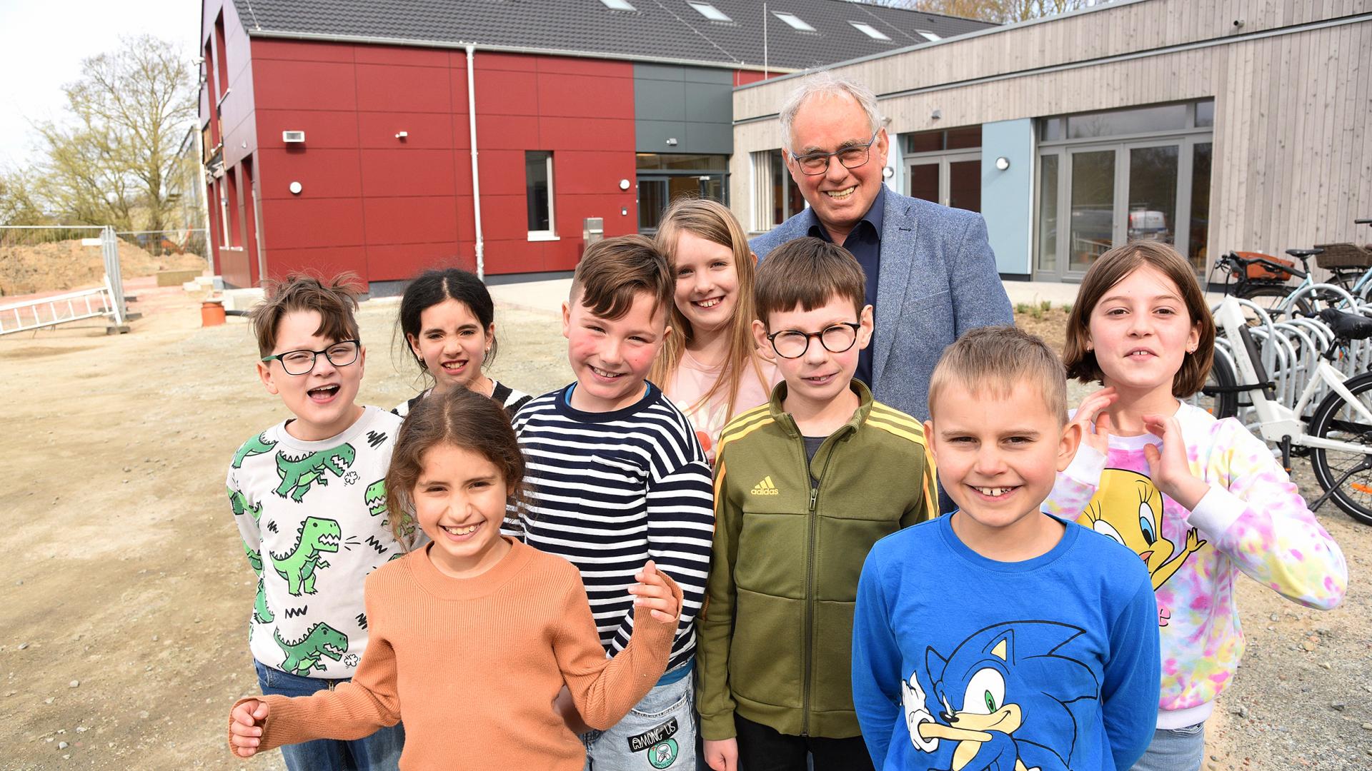 Kindergruppe und Grundschulleiter vor Schulgebäude