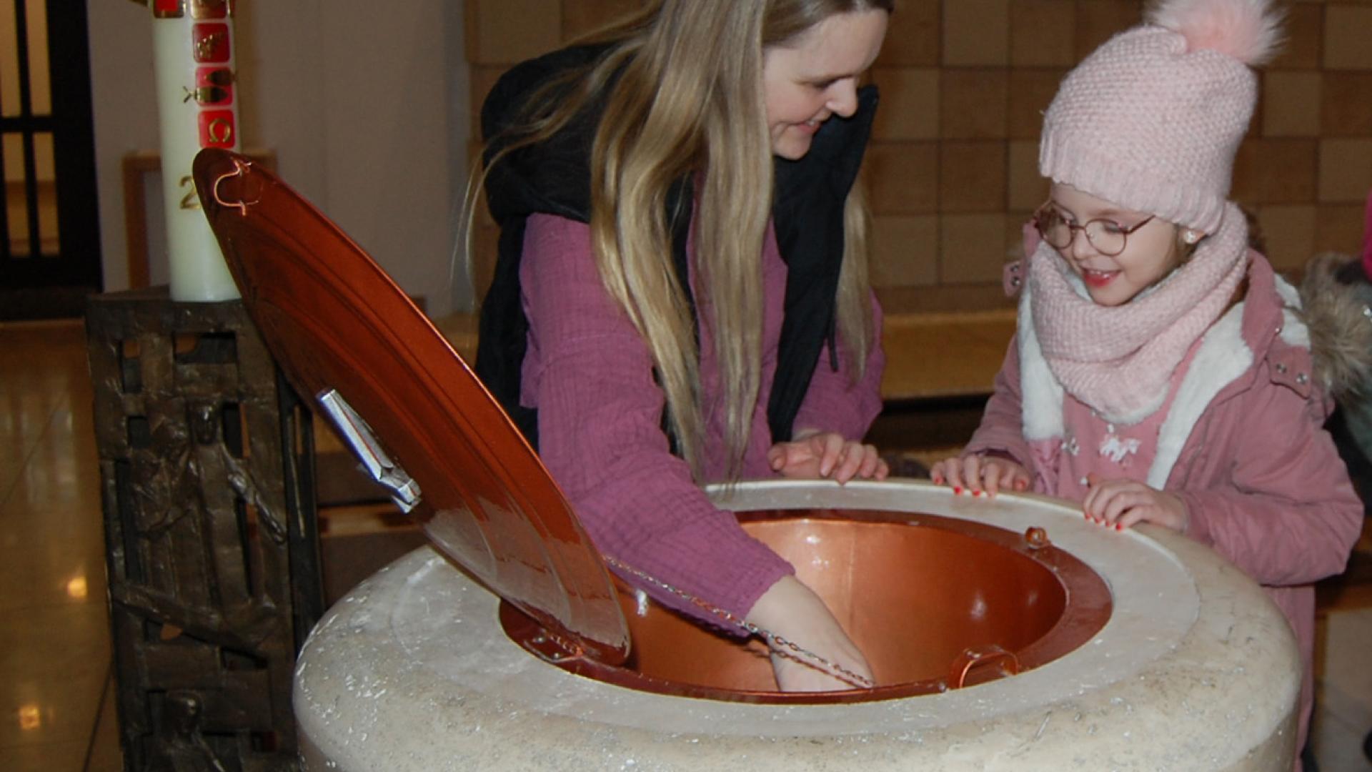 Eine Frau und ein Kind am Taufbecken.