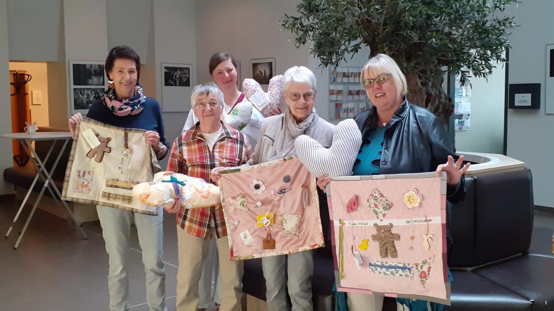 Fünf Frauen mit genähten Kissen und Decken