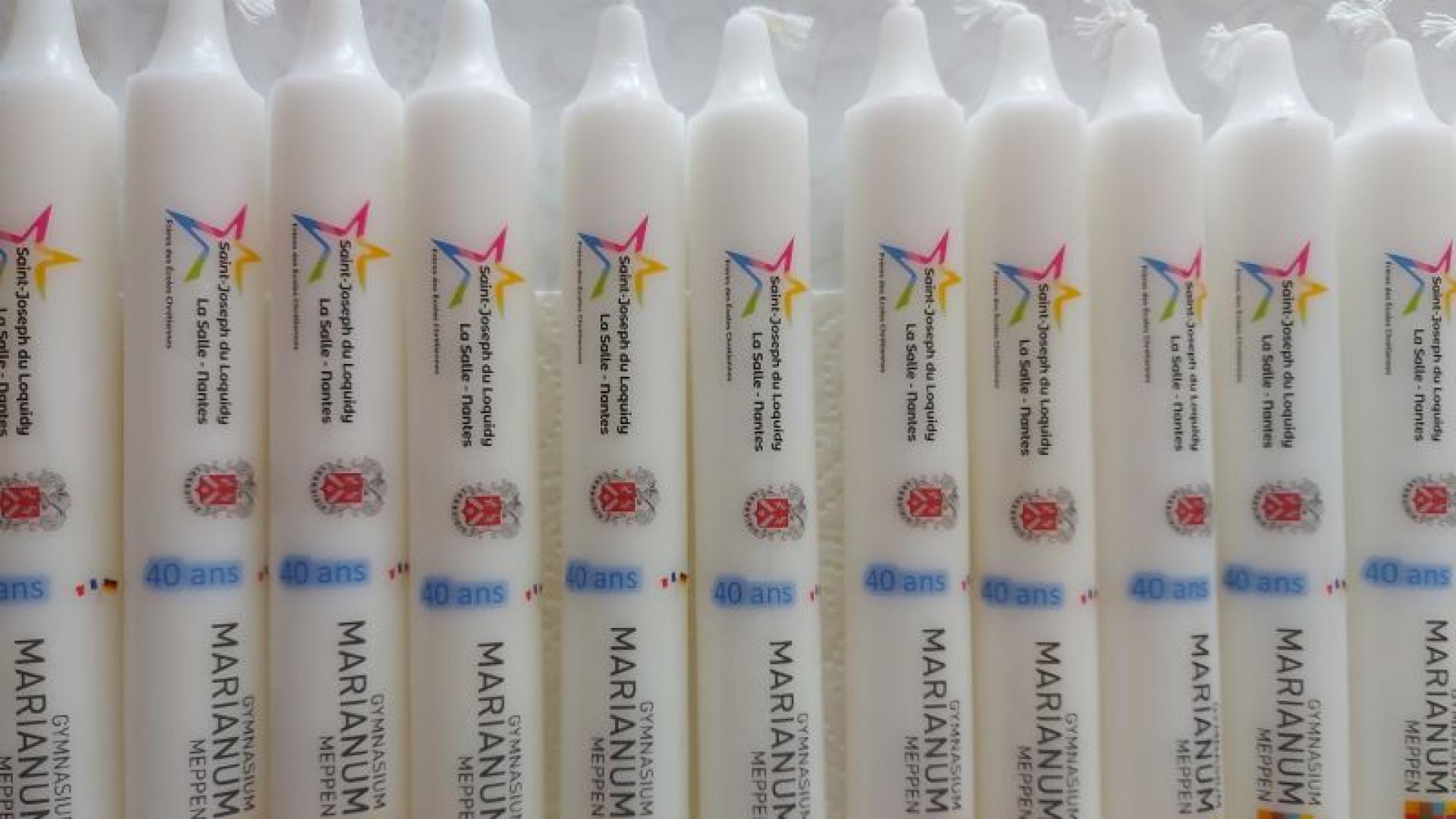 Mehrere Kerzen mit Inschriften, die auf beide Schulen verweisen