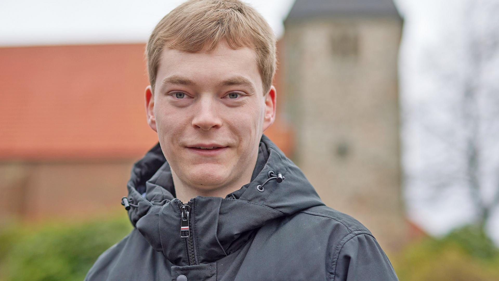 Ein junger Mann steht vor einem Kirchengebäude