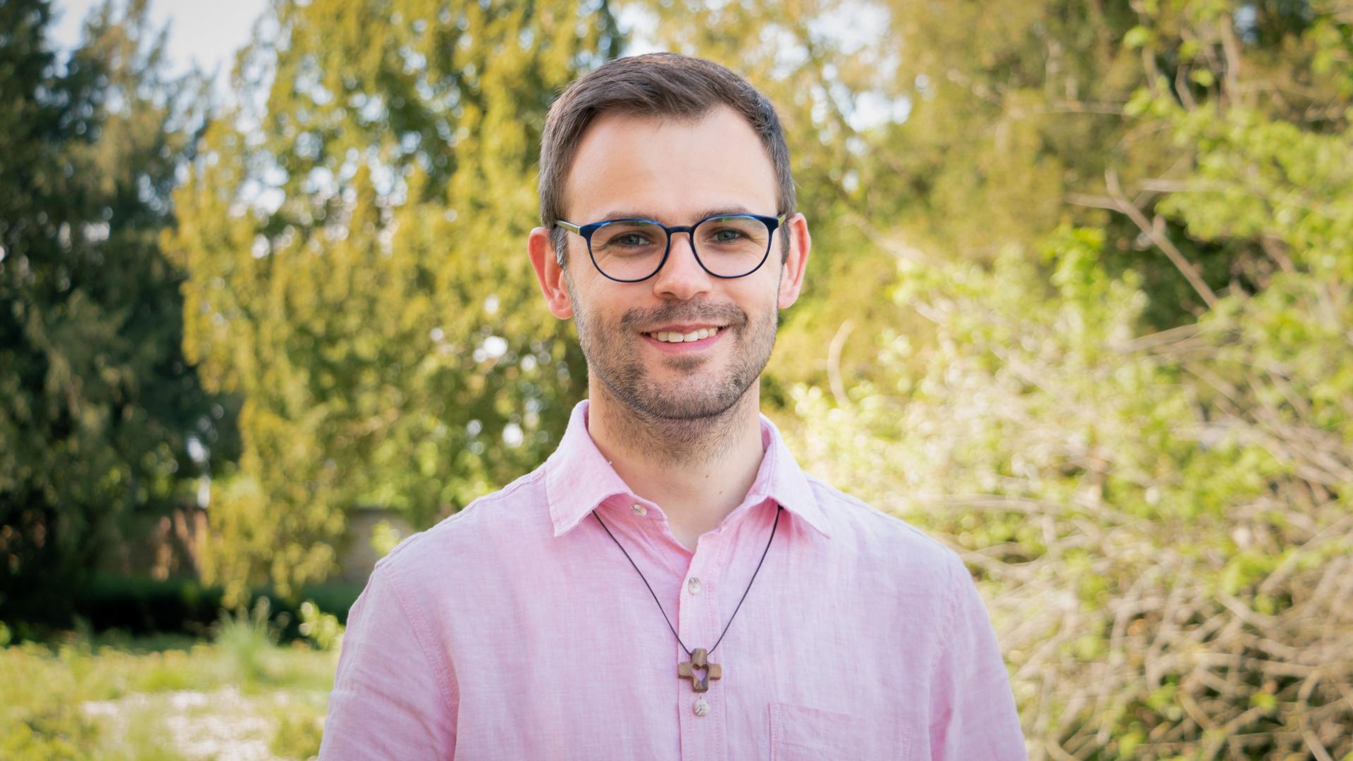 Ein junger Mann, der ein kleines Kreuz um den Hals hängen hat